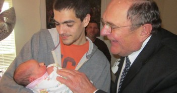 Stock photo a young man holding a baby with an older man looking on