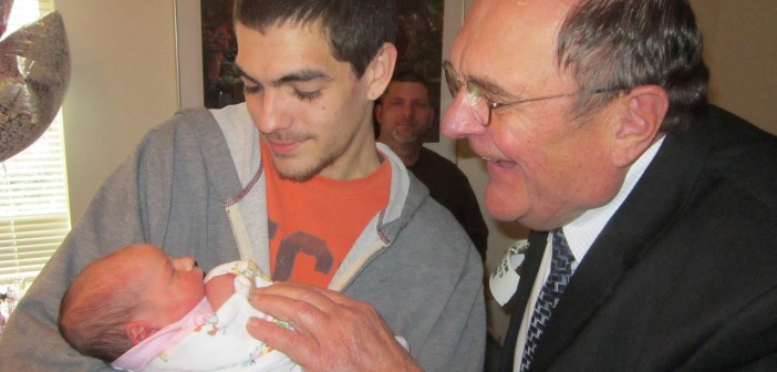 Stock photo a young man holding a baby with an older man looking on
