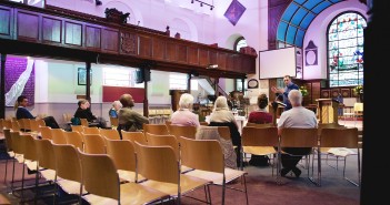Stock photo of a mostly empty worshiping space with some people listening to a sermon