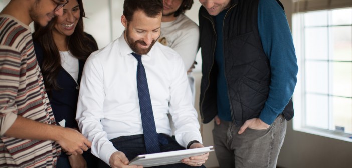 Stock photo of a group of mixed race and gender young professionals looking over a project