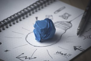 Stock photo of a crumpled up blue piece of paper on top of a drawing of a lightbulb