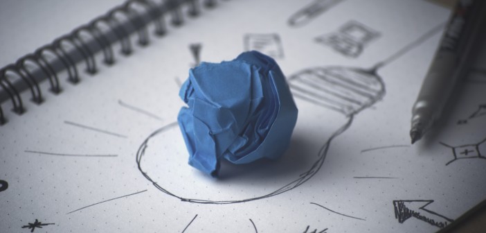 Stock photo of a crumpled up blue piece of paper on top of a drawing of a lightbulb