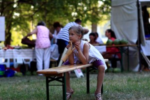Stock photo of a young white girl sitting on a bench at a community picnic