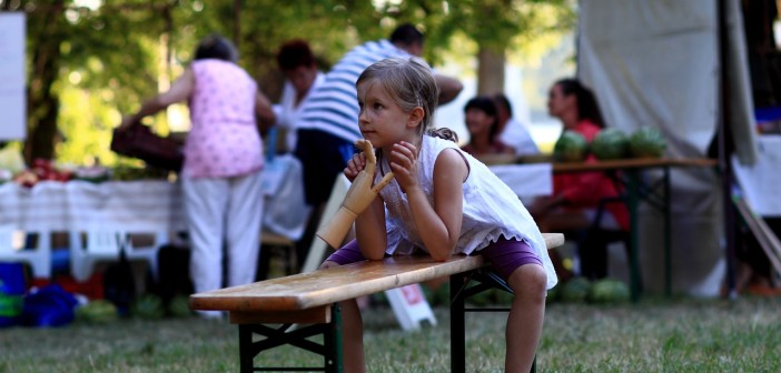 Stock photo of a young white girl sitting on a bench at a community picnic
