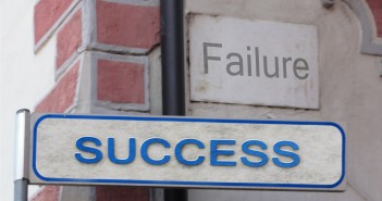 Stock photo of a street sign that says "SUCCESS" on it with a sign that says "FAILURE" in the background