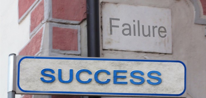 Stock photo of a street sign that says "SUCCESS" on it with a sign that says "FAILURE" in the background