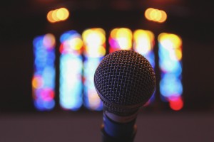 Stock photo of a stand microphone inside a worship space with stained glass windows