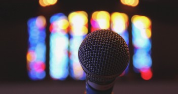 Stock photo of a stand microphone inside a worship space with stained glass windows