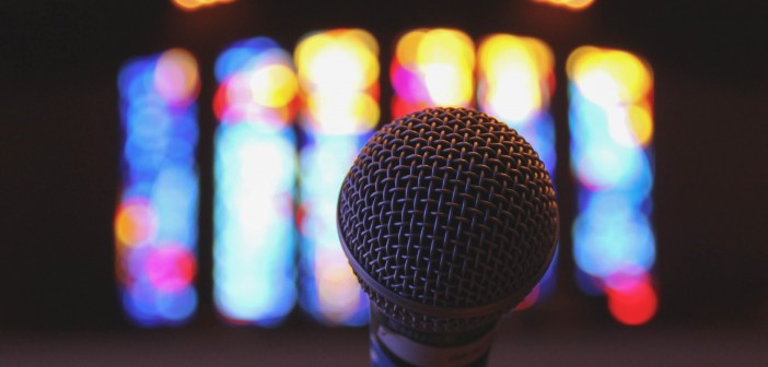 Stock photo of a stand microphone inside a worship space with stained glass windows