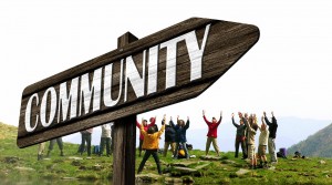 Stock photo of a signpost that points to "COMMUNITY" with a group of people standing in a circle behind it