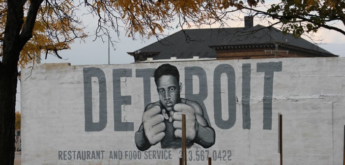 Stock photo of a white wall with "DETROIT restaurant and food service" and a young African American man with his fists up painted on it