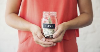 Photo of a young person holding a glass jar of money marked "Give"