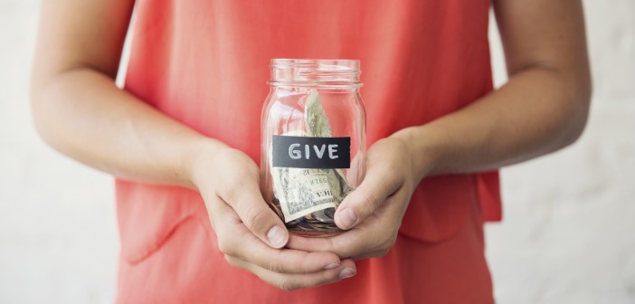 Photo of a young person holding a glass jar of money marked "Give"