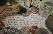 Cash and coins lying atop a Bible