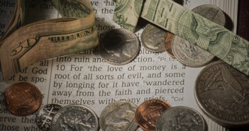 Cash and coins lying atop a Bible