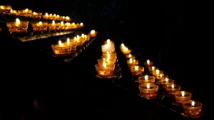 Stock photo of a bunch of lit votive candles in the dark