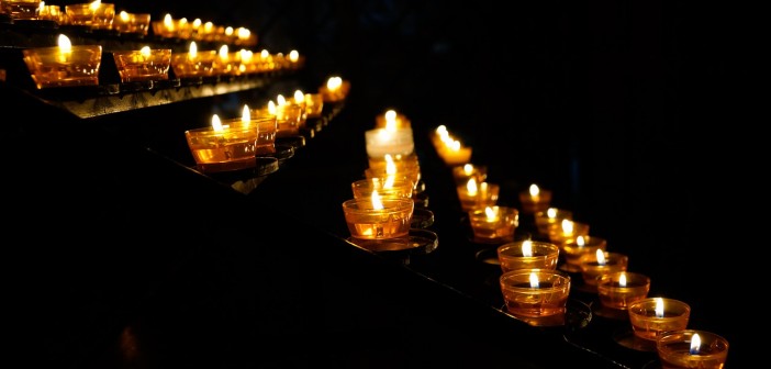 Stock photo of a bunch of lit votive candles in the dark