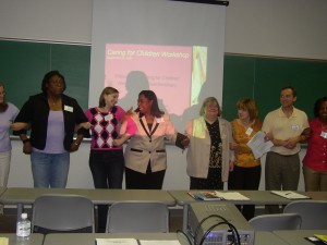 Photo of adults in classroom with arms linked in a group exercise