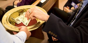Image of person placing money into an offering plate