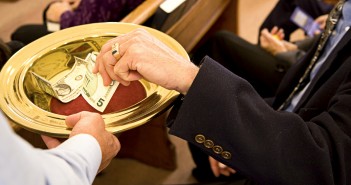 Image of person placing money into an offering plate