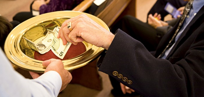 Image of person placing money into an offering plate