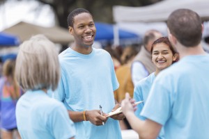 Photo of a group of smiling people holding clipboards at an outside event