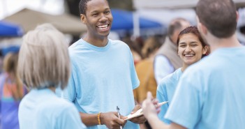 Photo of a group of smiling people holding clipboards at an outside event