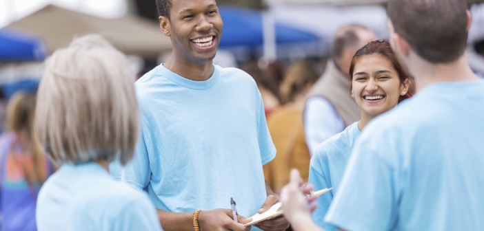 Photo of a group of smiling people holding clipboards at an outside event