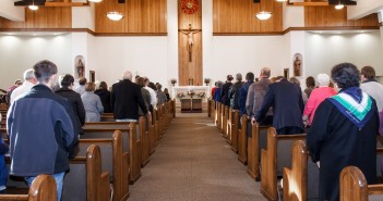 Stock photo of a full sanctuary with a crucifix at the front and center of the altar