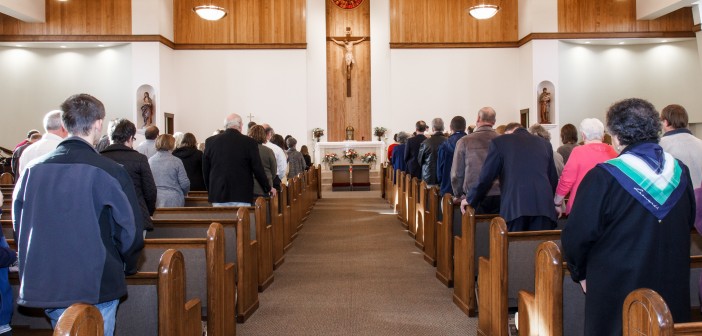 Stock photo of a full sanctuary with a crucifix at the front and center of the altar