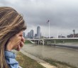 Stock photo of a woman with her face buried in her hand standing by a city waterfront