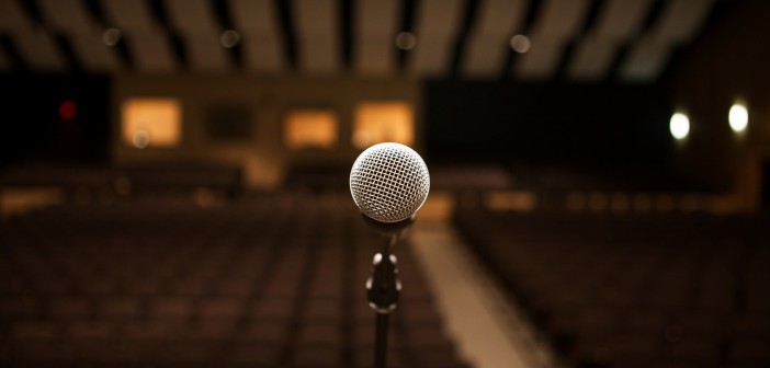 Stock photo of a stand microphone presumably on a stage facing an empty auditorium