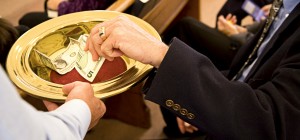 Image of a person placing money in an offering plate at church