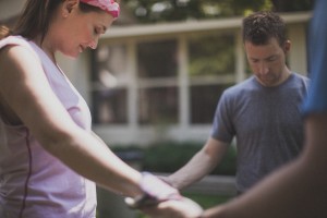 Stock photo of a group of at least three people holding hands in a circle and praying outside
