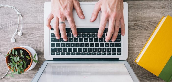 Overhead photo of hands typing on a laptop computer