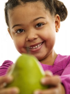 Photo of a smiling young girl offering a pear