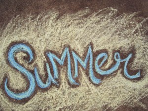 The word SUMMER written in sidewalk chalk against a yellow background