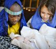 Photo of children playing Mary, Joseph, and baby Jesus in a live nativity scene