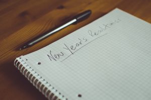 Note book on a table with New Year's Resolutions written on the top of it