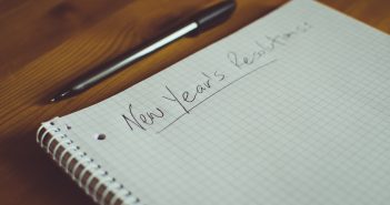 Note book on a table with New Year's Resolutions written on the top of it