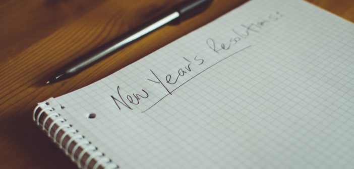 Note book on a table with New Year's Resolutions written on the top of it