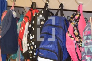 A row of multi-colored backpacks hanging up. Providing material resources, like backpacks, is one way schools can benefit from partnerships with churches.