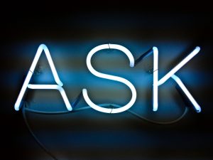 Blue neon sign that says ASK. Asking