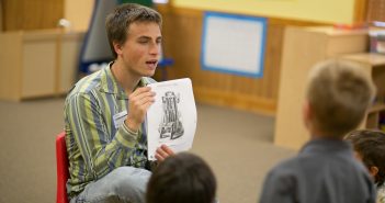 A young adult reading to a group of kids and engaged in his church's partnership with the local school