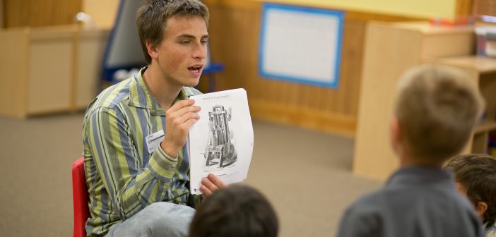 A young adult reading to a group of kids and engaged in his church's partnership with the local school