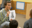 Teacher showing a photo in a book to students in a classroom