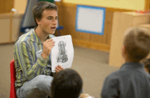 Teacher showing a photo in a book to students in a classroom