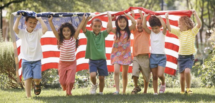 Photo of a diverse group of children running with an American flag, which highlights the coming demographic shift. CREDIT: Ariel Skelley / Blend / Learning Pictures / Universal Images Group