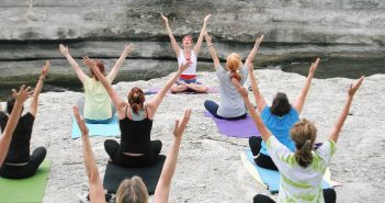 Photo of a group of people doing yoga outside by a stream