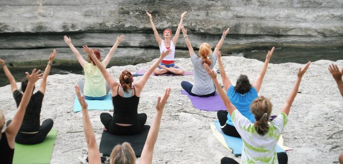 Photo of a group of people doing yoga outside by a stream